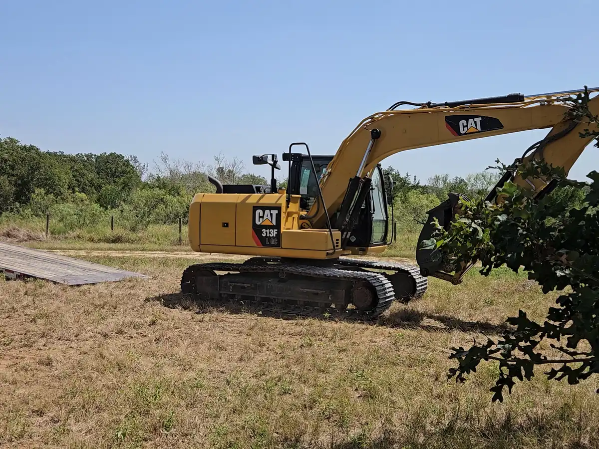Excavator on cleared ground by the tree line